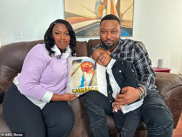 Jasmine Watson sits with her partner, Cedric Dean, and their 4-year-old son Chase. Pictured on the pillow is Chance Dean, who died of NEC in March 2020.