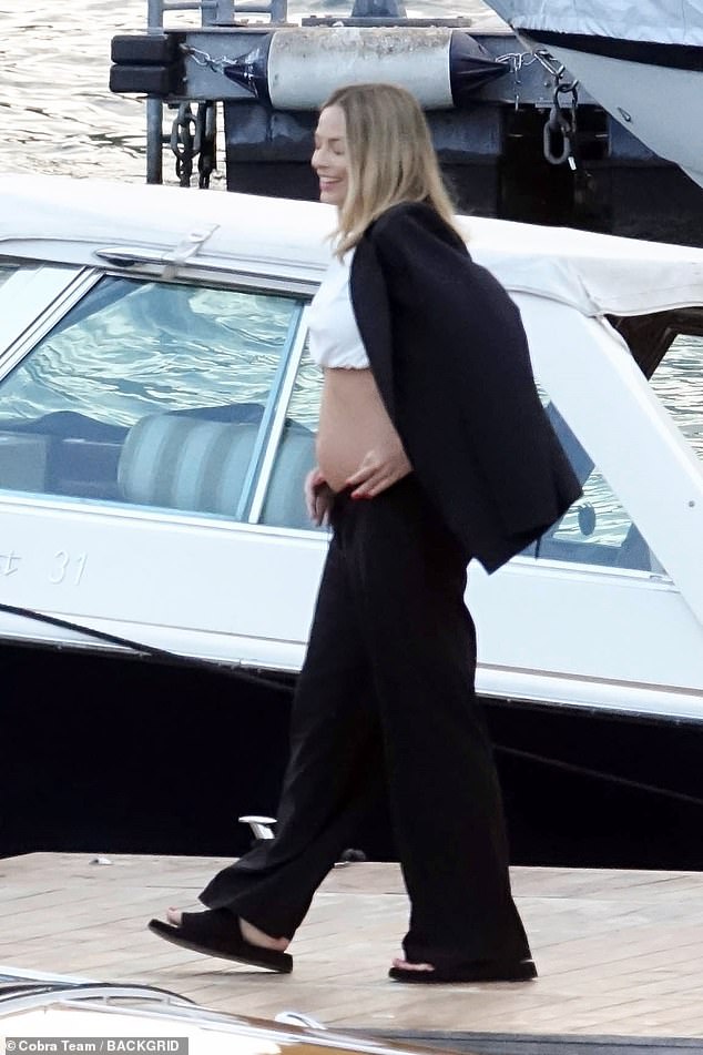 She completed her look with a sleek black blazer and accessorized with a cream leather handbag as she was given a hand to get off the boat.