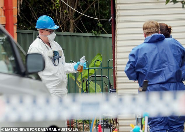 Pictured: A forensic investigator removed a bottle containing a brown petroleum-like liquid from the scene where three children were burned to death.