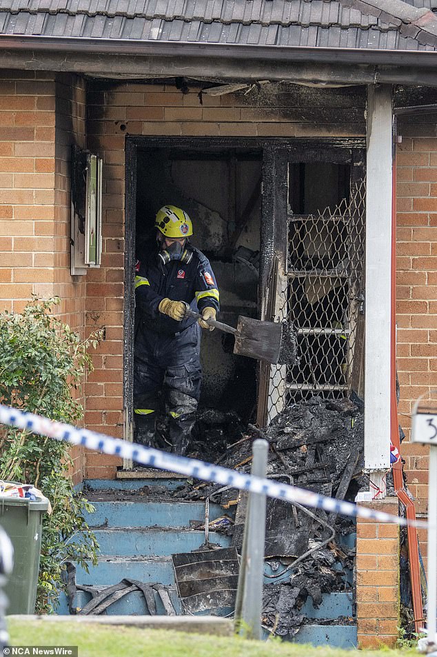 Pictured: A fire and rescue worker removing soot and debris from the property on Sunday.