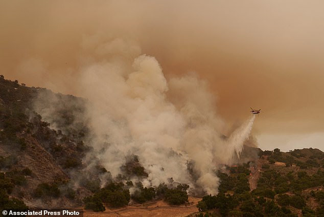 A helicopter drops water on the flames of the Lake Fire in Los Olivos, California, Saturday, July 6, 2024. (AP Photo/Eric Thayer)