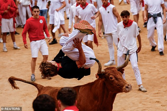 A reveller jumps over a wild cow at the San Fermin festival in Pamplona