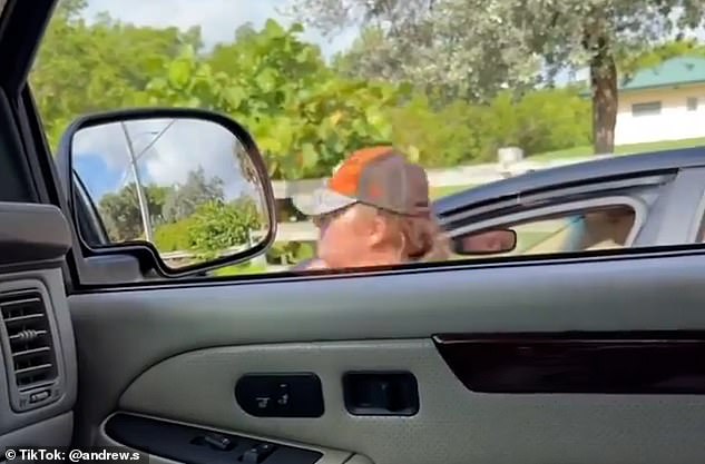 Shared on Reddit, the chaotic video begins with the woman sitting in the driver's seat with the door open to yell at the male motorist filming from his car a few feet away, before approaching his car.