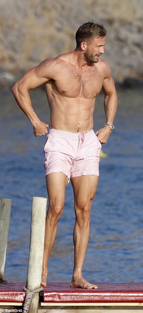 He showed off his impressive muscular form in just a pair of light pink striped swim trunks.