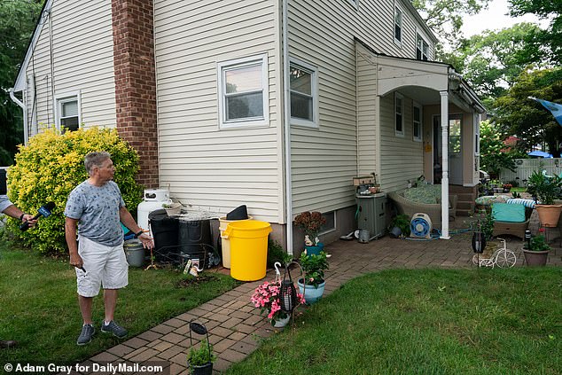 Rex Heuermann's neighbor Etienne Devilliers shows where Heuermann used to look over the backyard fence at his wife sunbathing at their home in Massapequa Park, New York.