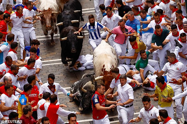 The 'mozos' are chased by a group of bulls from the Herederos de Victoriano del Río cattle farm as they run together through the streets during the third running of the bulls of the San Fermin festival in Pamplona, ​​northern Spain, on Tuesday.