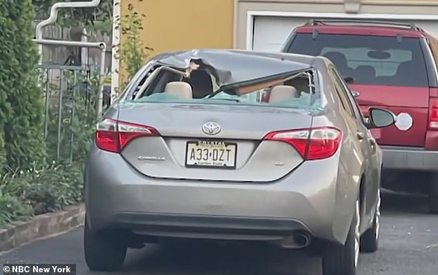 In the image: A car is seen with its rear windshield completely shattered by shrapnel.