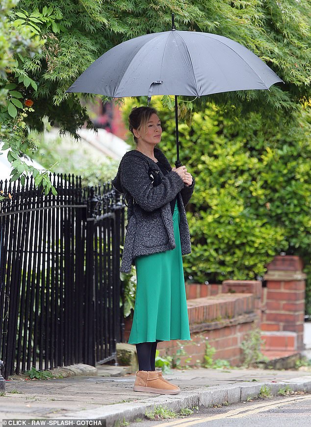 At one point she was dressed in a striking green skirt and a fluffy grey jacket while trying to keep dry with a large umbrella.