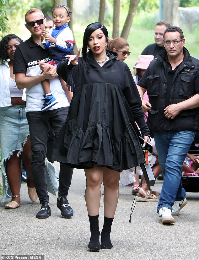 Cardi looked glamorous for the outdoor occasion in an oversized black hooded dress and booties.