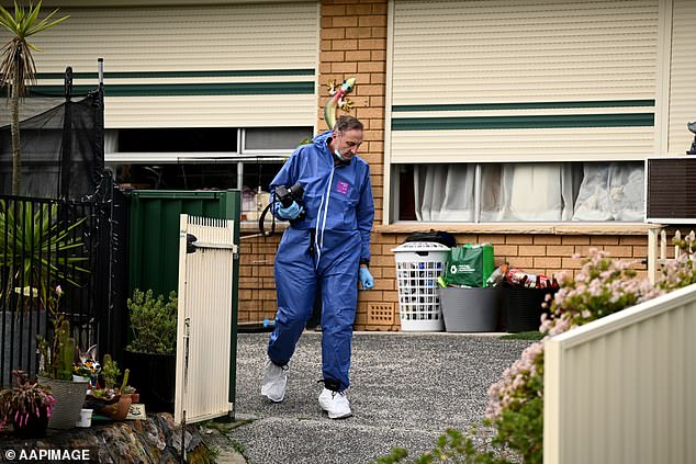 A forensic officer is seen leaving the house, clutching a camera.