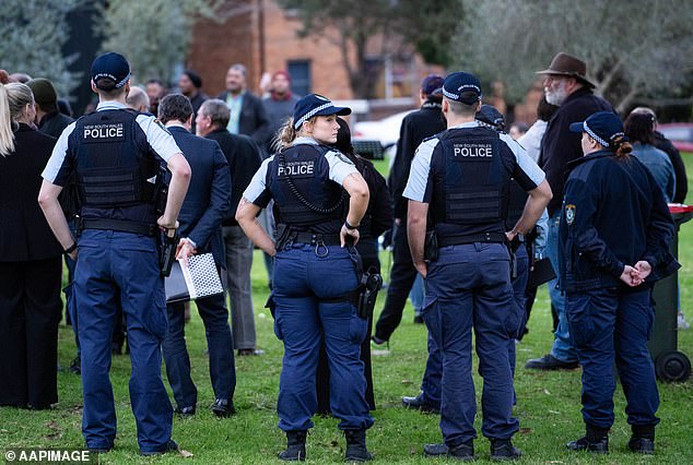 Local police officers attend a community vigil Thursday for the three young children who died in a house fire in Lalor Park on Sunday.