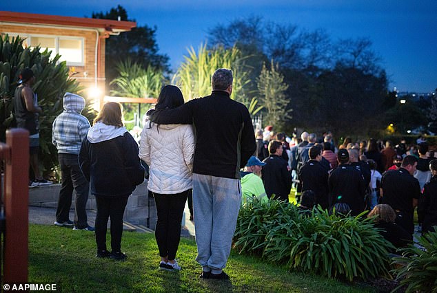 A couple support each other at Thursday night's vigil at Chifley Park in Lalor Park in memory of three young children allegedly killed in a house fire.