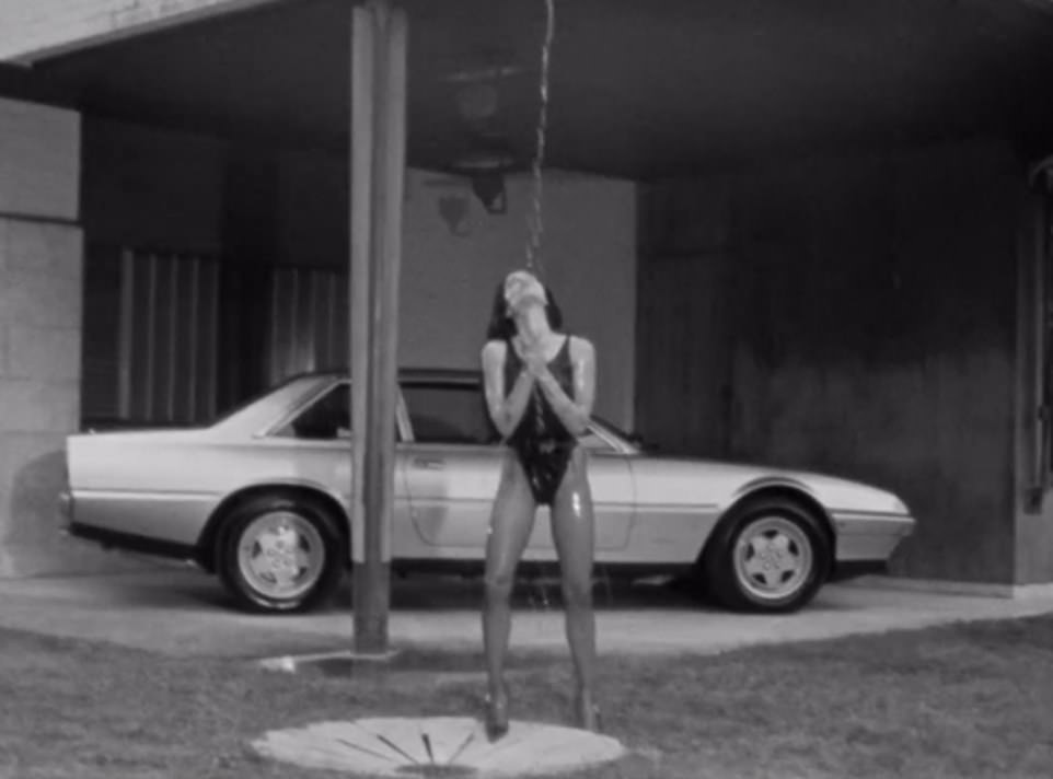 Here she is seen with water dripping on her while a vintage car can be seen in the background.