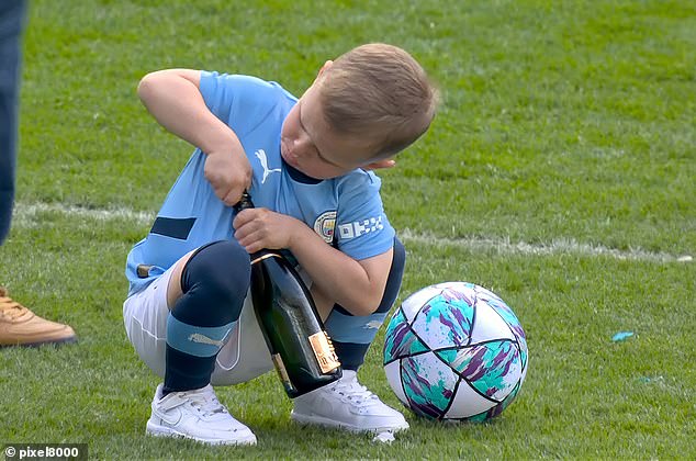 Photographers captured the moment little Ronnie Foden, 5, attempted to open a bottle of champagne as his father Phil celebrated with his Manchester City teammates after their historic win on Sunday afternoon.