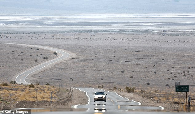 A vehicle drives by as heat waves shimmer on the asphalt. Death Valley is the hottest and driest place in the United States