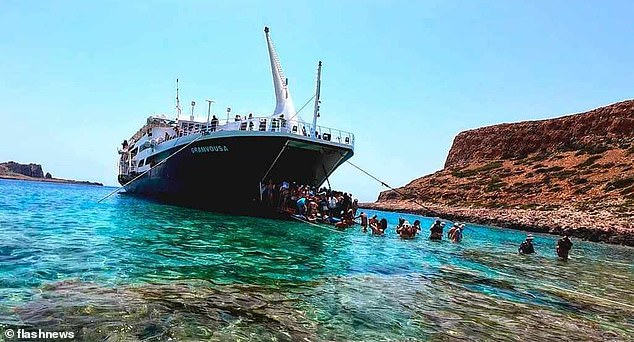 Passengers can be seen disembarking from the ferry's hatch and making their way through the water.