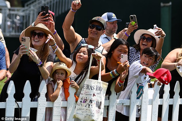 Fans react as NFL football player Travis Kelce passes by on his way to the 17th hole