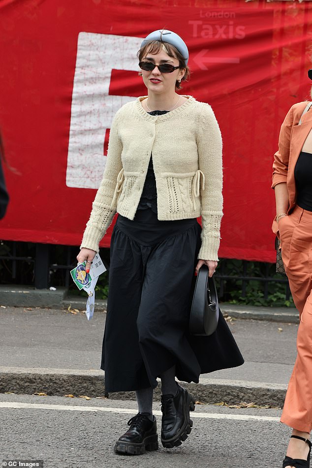 Maisie Williams showed off her unique style in a cream cardigan, black dress and chunky loafers.