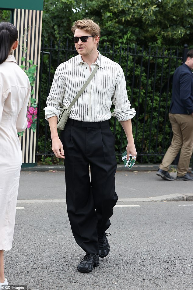 Joe Alwyn dressed to impress in a white shirt and black trousers.