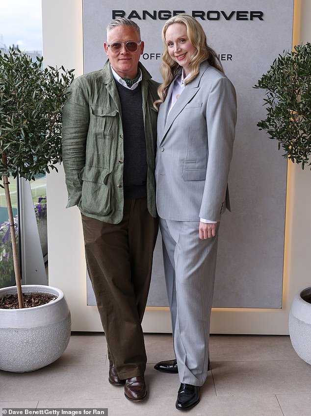 The celebrity also took the opportunity to be photographed with British fashion designer Giles Deacon, who cut a dapper figure in a dark grey knitted vest and brown trousers.