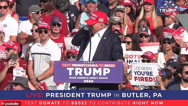 Donald Trump holds his ear while a gunman aims at him