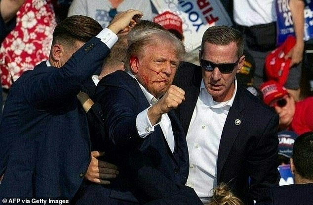 Donald Trump is seen with blood on his face surrounded by secret service agents