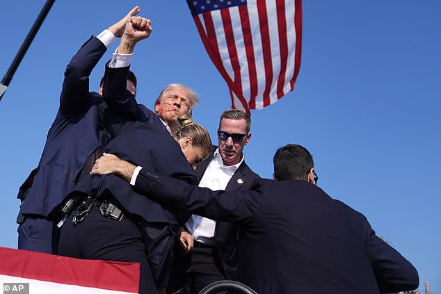 Donald Trump is seen with his fist in the air beneath a Stars and Stripes flag after Saturday's shooting in Butler, Pennsylvania, where the president was wounded and the shooter and a bystander were killed.