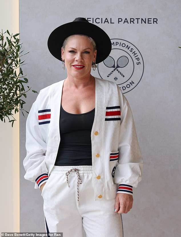 The 44-year-old singer, who recently showed off her bikini body while on vacation, posed for photos in a white cardigan and pants with navy and red striped detailing on the pockets and wrists of the outfit.