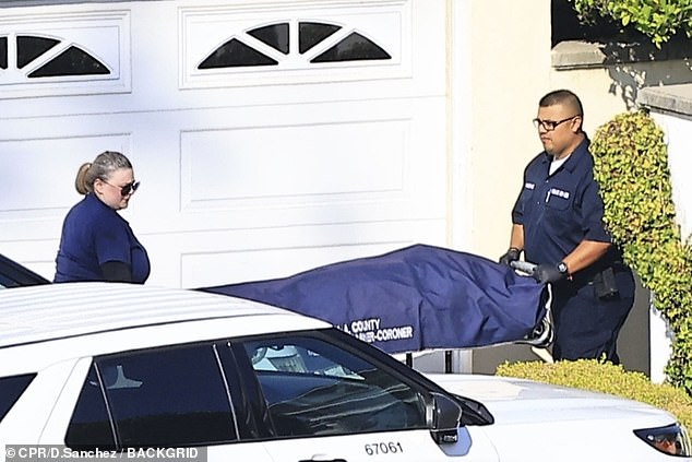 The footage shows the coroner wheeling Simmons' body out of his home on a stretcher.