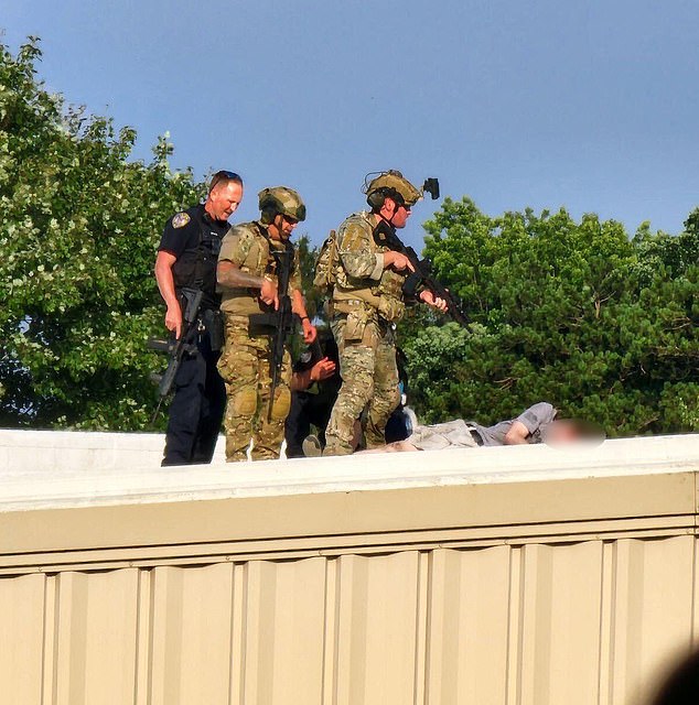 Police personnel stand over the body of Thomas Matthews Crooks on a rooftop.