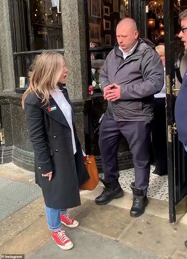 A security guard stands at the door as the woman has a fight with the staff member.