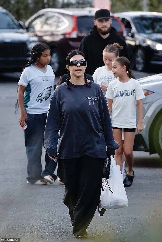 Kourtney, whose jet-black hair was styled in braids, and her mini squad were joined by a bearded bodyguard dressed in black, who towered over the five.