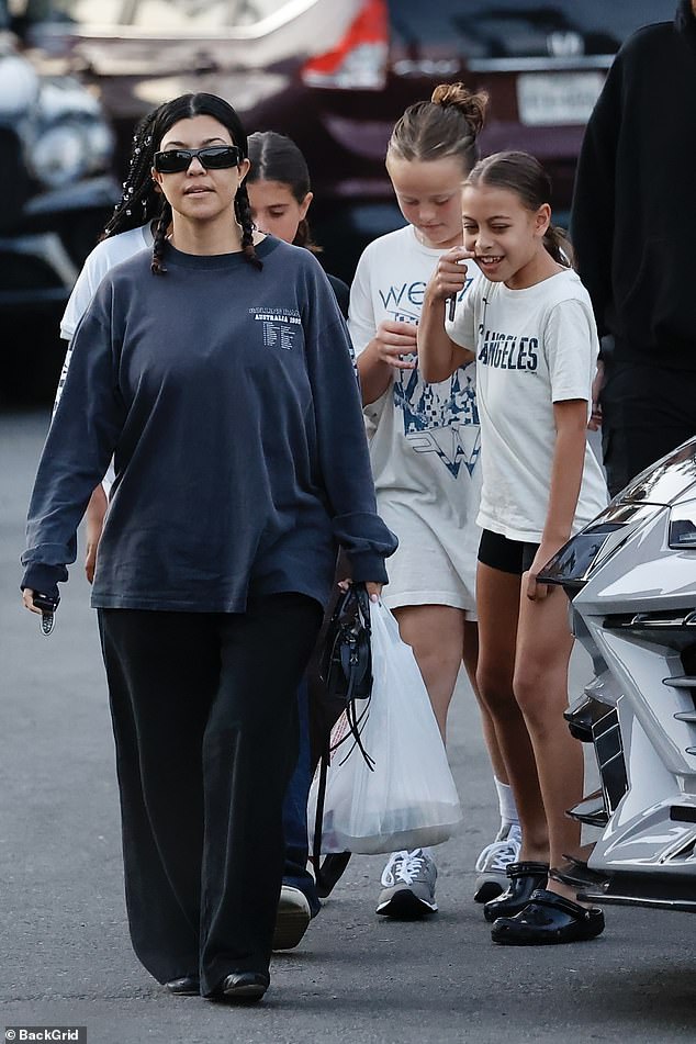 The 45-year-old mother of four borrowed her husband Travis Barker's navy long-sleeved shirt from the Rollins Band's 1992 Australian tour and paired it with loose-fitting black trousers and matching ballet flats for their family dinner.