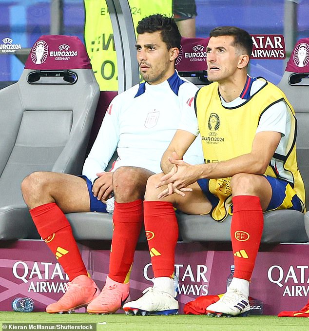 Rodri (left) takes his place on the bench for Spain after being substituted at half-time