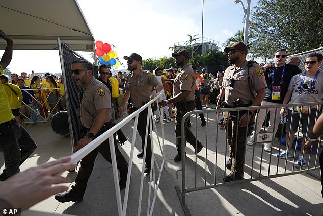 Police officers patrol as fans wait to enter the stadium ahead of the Copa America final