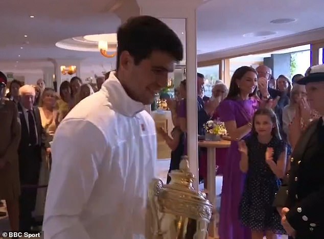 The tennis player appears in the image walking away with his trophy while the Royal Family applauds him.