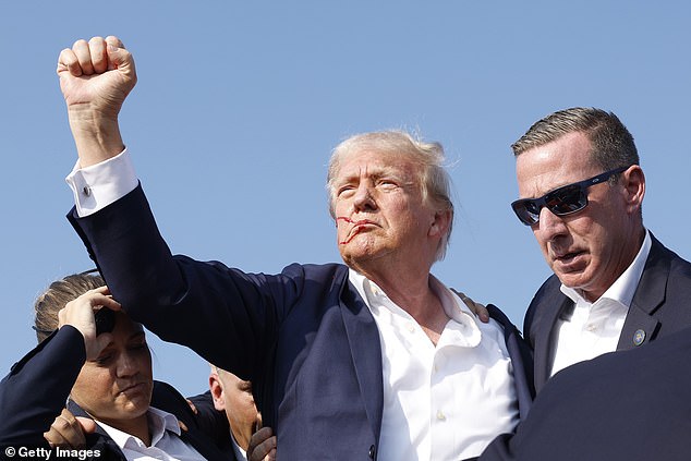 Trump manages to raise his clenched fist after standing up following the shooting