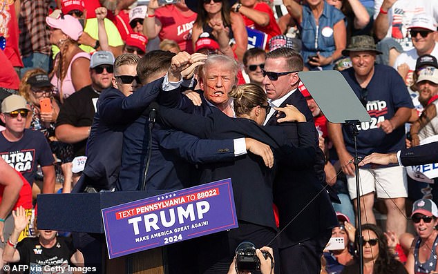 Donald Trump is seen with blood on his face as he is surrounded by Secret Service agents in an attempt to end his life at a campaign event in Butler, Pennsylvania.