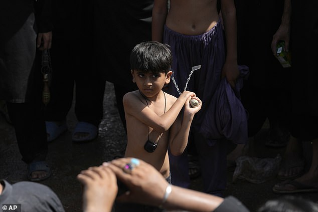 A Shia Muslim boy holds a knife tied to chains during a Muharram procession, in Islamabad, Pakistan, today