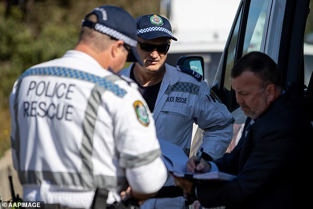 NSW Police rescue officers speak to a detective near a forest at Sandy Point Quarry in Menai (pictured) in July 2020