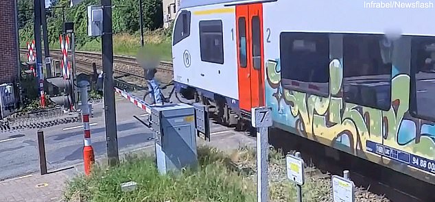 The moment the cyclist's bike gets trapped under the train and flies away