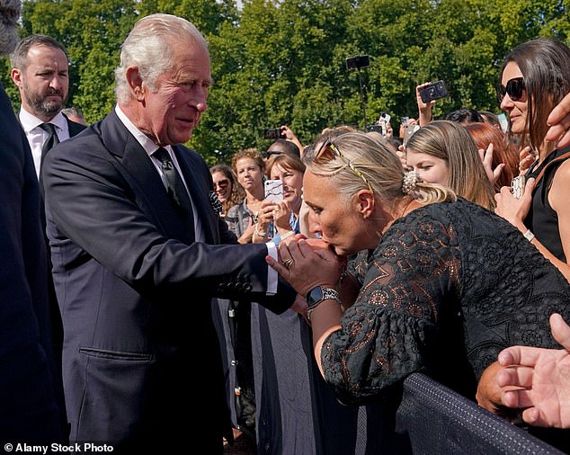 A royal admirer kisses King Charles' hand during a walk outside Buckingham Palace following the death of his mother Queen Elizabeth, September 2022