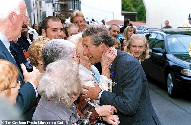 Prince Charles is kissed by an elderly woman during a visit to Cwmaman, Aberdare, Wales, in 2001