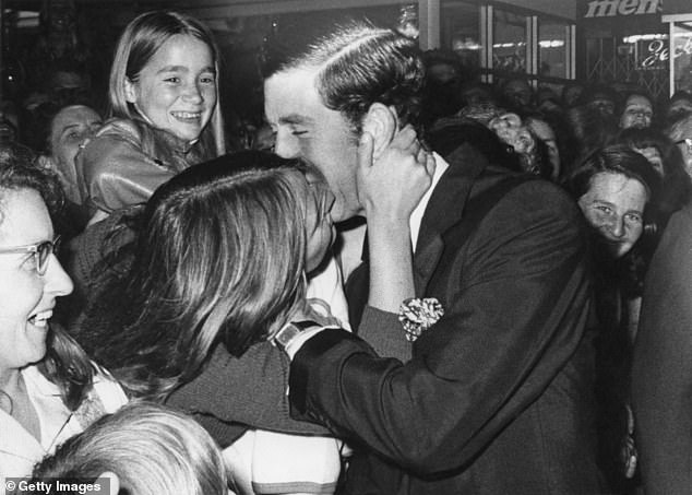 Prince Charles receives a kiss from sixteen-year-old Gilda Larbey during a stroll through the shopping centre of Perth, Western Australia, in November 1977.