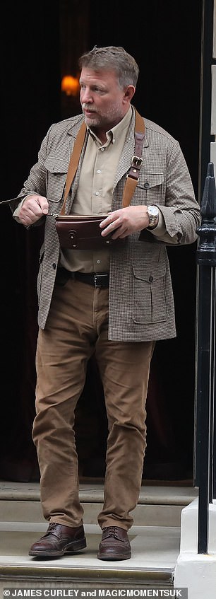 Guy paired his look with a smart beige shirt and tan trousers, finished off with a matching leather wallet.