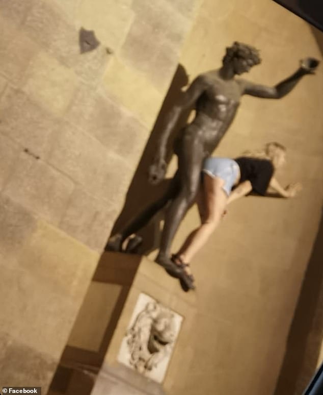 The smiling woman, wearing denim shorts and a black T-shirt, was also standing in front of the sculpture as she read while her friend took photos.