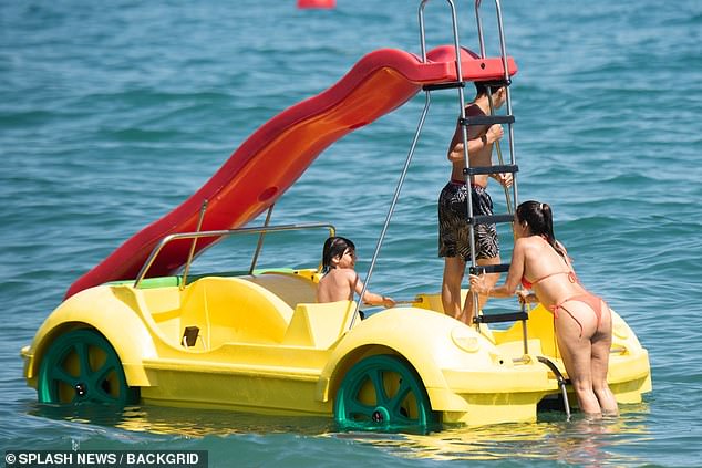 They were seen boarding a car-shaped pedal boat, complete with a water slide, during their fun day outdoors.