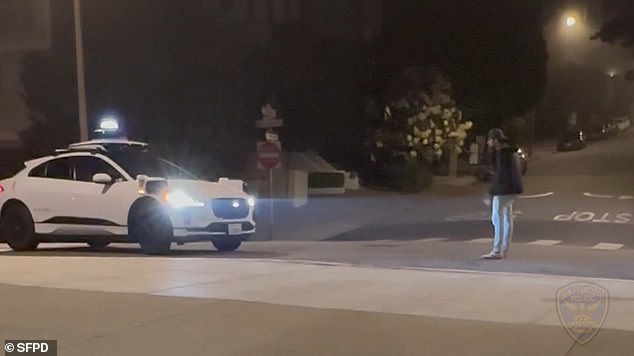 He stood in front of the white car in the middle of the road, preventing it from moving as the artificial intelligence refused to risk running him over.