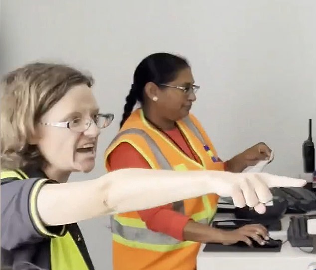 The bizarre moment begins with the bespectacled female officer, dressed all in black and a neon yellow vest, shouting at the crowd. (Pictured: her shouting alongside her co-worker)