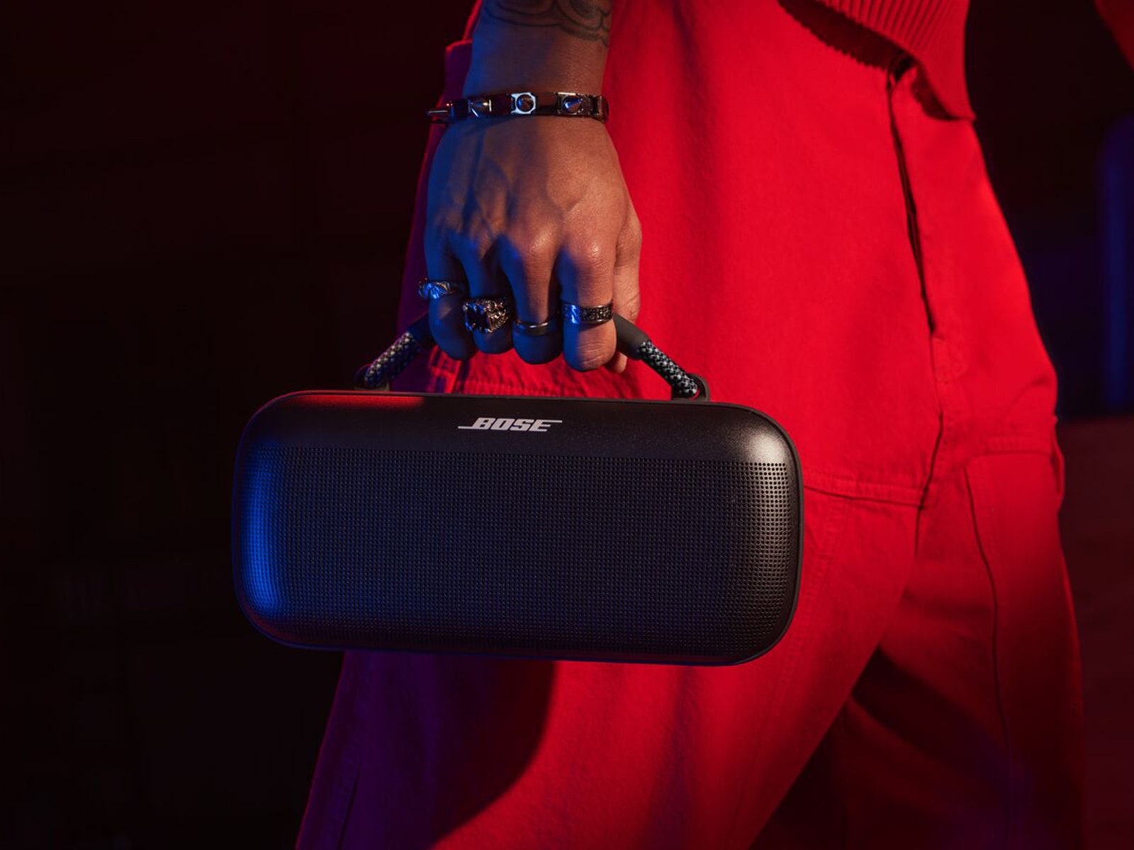 Close-up of a person dressed in red while holding a black portable speaker